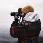 person in gray hoodie using black binoculars